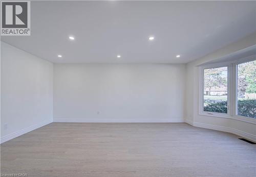 Expansive room featuring wood-finish flooring, recessed lighting, and a prominent bay window - 210 Ferguson Avenue, Cambridge, ON 