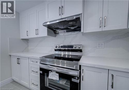 White shaker cabinetry, stainless steel range hood, electric range, light-toned countertops, and a patterned backsplash - 210 Ferguson Avenue, Cambridge, ON 