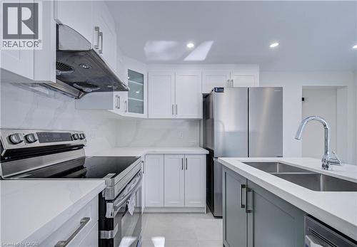 White shaker cabinetry, stainless steel appliances, white countertops, kitchen island with undermount double-basin sink, and recessed lighting - 210 Ferguson Avenue, Cambridge, ON 