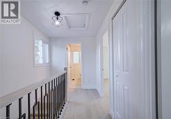 Light wood-finish flooring, white walls, and a modern geometric ceiling light fixture - 