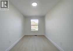 Bright room featuring light-toned wood-finish flooring, a single window, and a flush-mount ceiling light - 