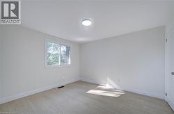 Light-colored wood-finish flooring, white walls, white trim, a single window, and a flush-mount ceiling light fixture - 