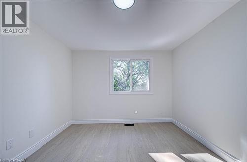 Smooth white walls, wood-finish flooring, white window trim, and a ceiling-mounted light fixture - 210 Ferguson Avenue, Cambridge, ON 