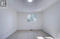 Smooth white walls, wood-finish flooring, white window trim, and a ceiling-mounted light fixture - 