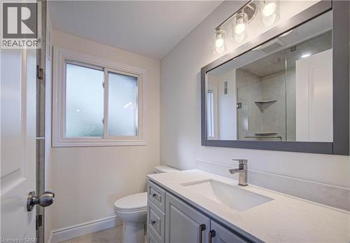 Frosted window, sleek vanity with integrated sink, contemporary vanity lighting, frameless mirror, and modern brushed nickel faucet - 210 Ferguson Avenue, Cambridge, ON 
