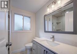 Frosted window, sleek vanity with integrated sink, contemporary vanity lighting, frameless mirror, and modern brushed nickel faucet - 