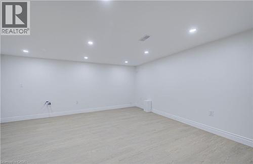 Recessed lighting illuminates the open area with light wood-finish flooring and white walls - 210 Ferguson Avenue, Cambridge, ON 