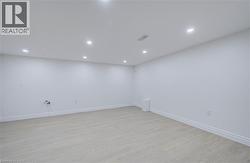 Recessed lighting illuminates the open area with light wood-finish flooring and white walls - 