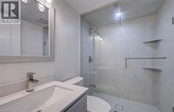 Bathroom featuring a glass-enclosed shower with integrated shelving, a sleek vanity with an undermount sink, and a framed mirror with integrated lighting - 