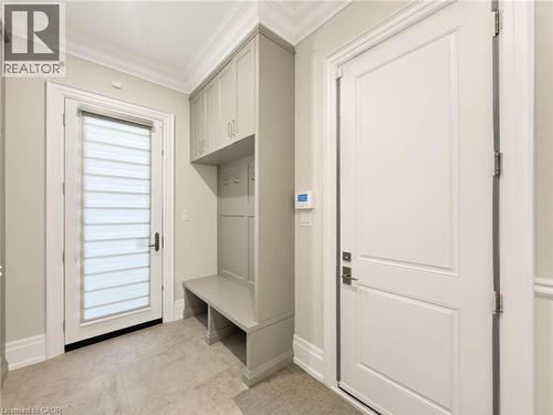Built-in cabinetry with bench seating and storage, tiled flooring, crown molding, and a paneled interior door - 236 Poplar Drive, Burlington, ON 