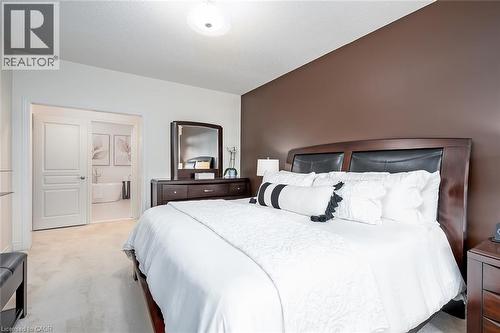 Light-colored carpeting, dark accent wall, recessed ceiling light, and a wood-finish bed frame - 4285 Couples Crescent, Burlington, ON 