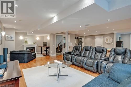 Recessed lighting, wood-finish flooring, white fireplace, built-in staircase, and wall sconces - 4285 Couples Crescent, Burlington, ON 