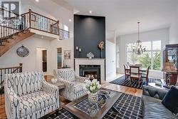 Two-story living area with hardwood flooring, a fireplace, and a built-in staircase with iron balusters - 