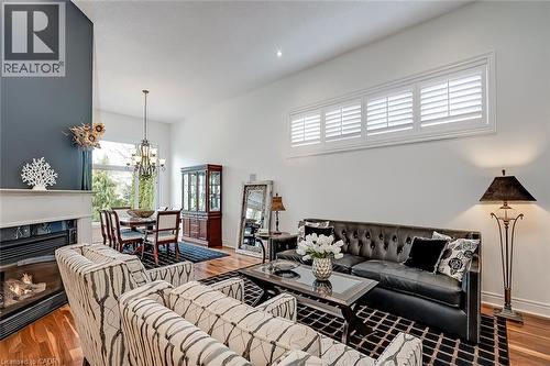 Hardwood flooring, high ceilings, fireplace with mantel, transom windows with white shutters, and a chandelier - 4285 Couples Crescent, Burlington, ON 
