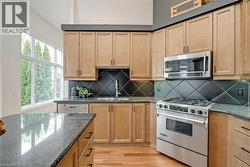 Wood-finish cabinetry complemented by dark countertops, stainless steel appliances, and a diagonal tile backsplash - 