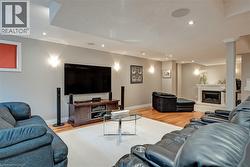 Hardwood flooring, recessed lighting, built-in ceiling speakers, wall-mounted sconces, and a gas fireplace with a mantel - 