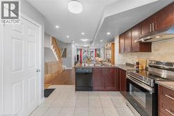 Kitchen featuring dark wood cabinetry, stainless steel appliances, and a tiled backsplash - 