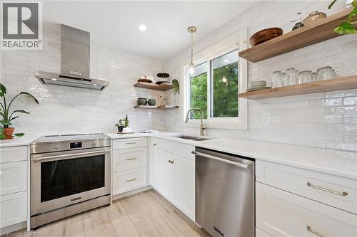 Modern kitchen featuring white shaker cabinets, stainless steel appliances, open shelving, and a subway tile backsplash - 8 Christian Street, Baden, ON 