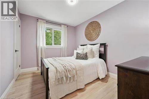 Light wood-finish flooring with white trim, a double-paned window, and an overhead flush-mount light fixture - 8 Christian Street, Baden, ON 