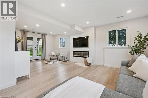 Recessed lighting illuminating wood-finish flooring, a linear electric fireplace, and French doors leading to exterior - 8 Christian Street, Baden, ON 