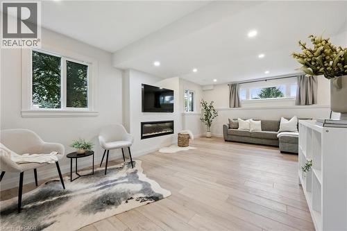 Recessed lighting, wood-finish flooring, white walls, multiple windows, and a built-in electric fireplace - 8 Christian Street, Baden, ON 