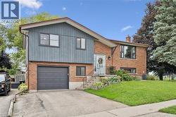 Split-level exterior featuring brick and vertical siding, attached garage, and a concrete driveway - 