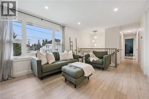 Expansive window offering abundant natural light, light wood-finish flooring, recessed lighting, open concept railing, and a contemporary pendant light fixture - 8 Christian Street, Baden, ON 
