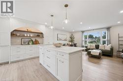 Open-concept layout featuring wood-finish flooring, recessed lighting, and a kitchen island with a light-toned countertop - 