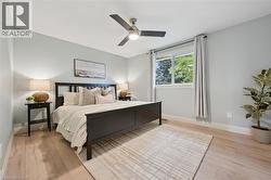 Light wood-finish flooring, a ceiling fan with integrated lighting, and a white-framed window - 