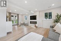 Recessed lighting illuminating wood-finish flooring, a linear electric fireplace, and French doors leading to exterior - 