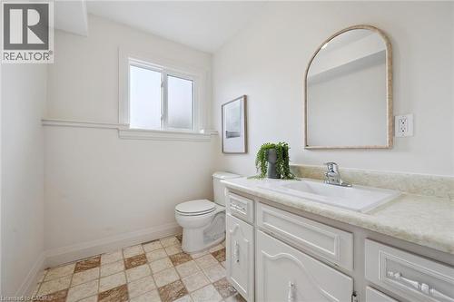 White vanity with integrated sink, chrome faucet, and arched mirror - 8 Christian Street, Baden, ON 