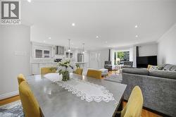 Open-concept living and dining area featuring recessed ceiling lights, pendant fixtures, and wood-finish flooring throughout - 