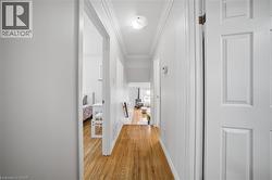 Bright hallway showcasing gleaming wood-finish flooring, crisp white painted walls, and clean-lined white six-panel doors - 