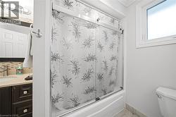 Modern full bathroom featuring a sliding glass shower enclosure with decorative frosted patterning, white subway tile surround, and chrome fixtures - 