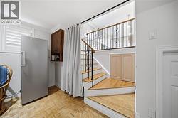 Bright, open foyer showcasing hardwood flooring, a prominent staircase with wooden treads and metal railings, and abundant natural light from multiple windows - 