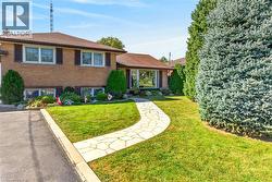 Brick exterior facade featuring a flagstone walkway, asphalt driveway, mature evergreen landscaping, and large picture windows - 