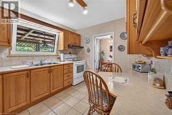 Kitchen featuring wood cabinetry, tiled backsplash, solid surface countertops, dual-basin stainless steel sink, and ceramic tile flooring - 