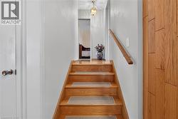 Staircase featuring wood treads with inset textile runners, a mounted wood handrail, and a decorative pendant light fixture - 