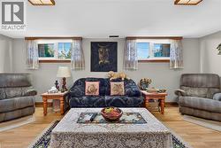 Wood-finish flooring, dual windows with wood trim, and square recessed lighting fixtures - 