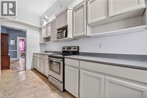 White cabinetry with dark countertops, stainless steel range, and a single basin sink - 199 N Locke Street N, Hamilton, ON 
