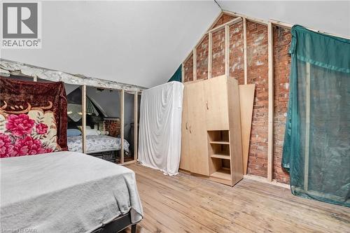 Exposed brick wall with wood framing, sloped ceiling, and wood-finish flooring - 199 N Locke Street N, Hamilton, ON 