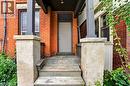 Brick exterior with stone window sills, wood-frame windows, and a covered porch featuring stone pillars and painted wood steps - 199 N Locke Street N, Hamilton, ON 