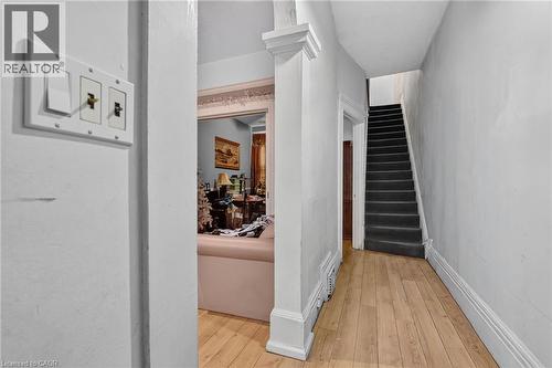 Hardwood-style flooring throughout the entry, staircase with dark carpeting, and white trim work - 199 N Locke Street N, Hamilton, ON 