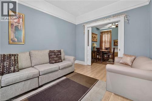 Light-toned wood-finish flooring, crown molding, and a wide cased opening with pocket doors - 199 N Locke Street N, Hamilton, ON 