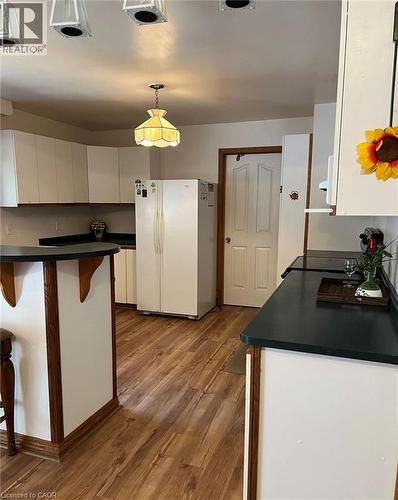 Wood-finish flooring throughout, complemented by white cabinetry and dark countertops - 16431 Highway 35, Algonquin Highlands, ON 