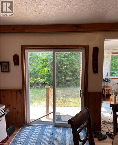 Sliding glass door leading to a concrete patio, featuring a wood railing - 16431 Highway 35, Algonquin Highlands, ON 