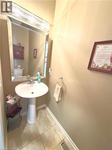 Pedestal sink with chrome faucet, framed mirror, and tile flooring - 40 Stornoway Crescent, Huron East, ON 