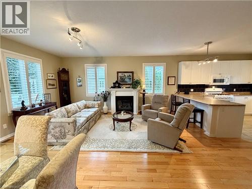 Hardwood flooring, fireplace, white plantation shutters, track lighting, kitchen island with seating - 40 Stornoway Crescent, Huron East, ON 