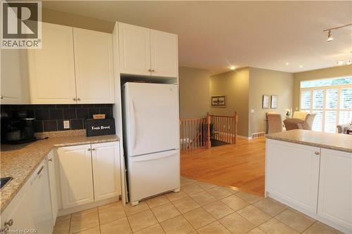 Kitchen featuring white cabinetry, a dark tile backsplash, and light-colored countertops - 40 Stornoway Crescent, Huron East, ON 