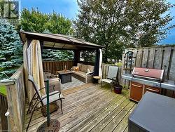 Wood deck with a covered gazebo featuring privacy curtains, surrounded by mature trees and a wood fence - 
